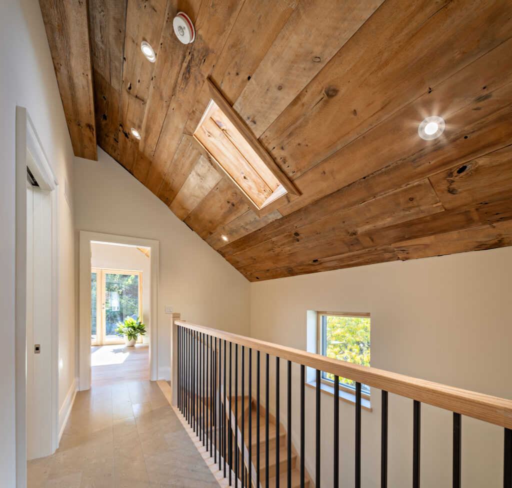 Top floor hallway. Reclaimed barn board and beams finish the top floor's vaulted ceiling. Photo Credit: Craig A. Williams.