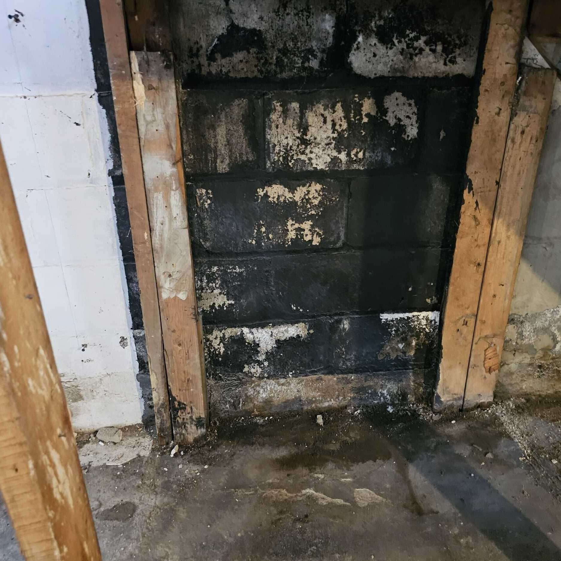 Fireplace renovation with black bricks and wooden framing in progress.