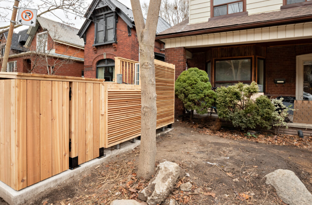 Outside. Looking at the front of the home. Shrubs conceal the heat pump unit while maintaining airflow.